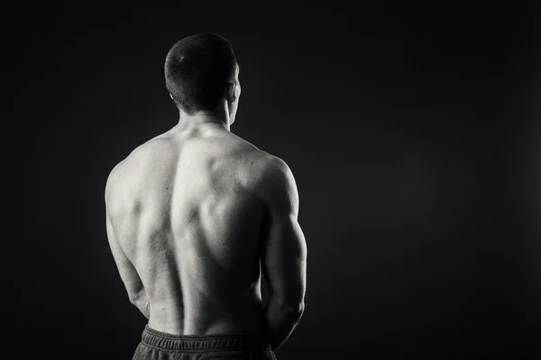 Profesyonel vücut geliştirmeci bedeni koyu arka plan üzerinde gösterir. — Stok fotoğraf