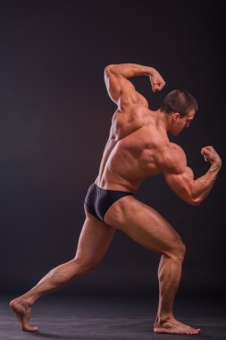 Profesyonel vücut geliştirmeci bedeni koyu arka plan üzerinde gösterir.