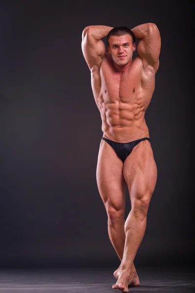 Professional bodybuilder shows his body on a dark background — Stock Photo, Image