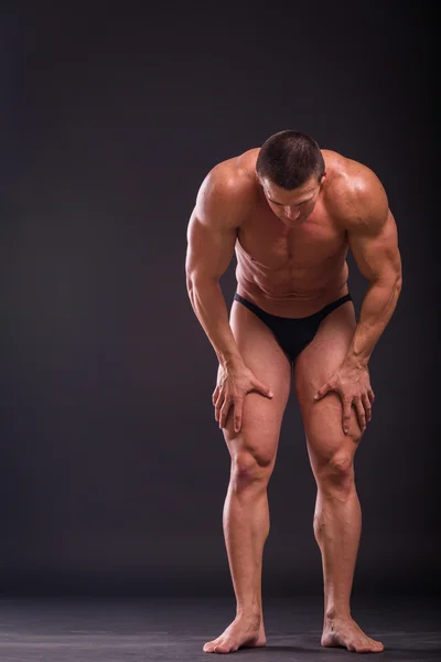 Professional bodybuilder shows his body on a dark background — Stock Photo, Image