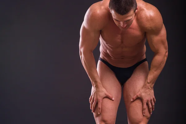 Professionele bodybuilder toont zijn lichaam op een donkere achtergrond — Stockfoto