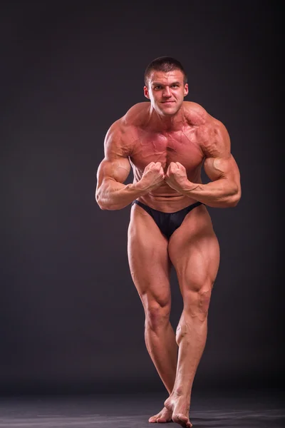 Bodybuilder professionnel montre son corps sur un fond sombre — Photo