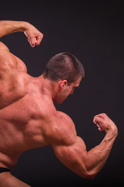 Bodybuilder professionnel montre son corps sur un fond sombre — Photo