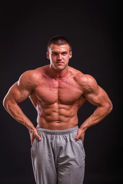 Professional bodybuilder shows his body on a dark background — Stock Photo, Image