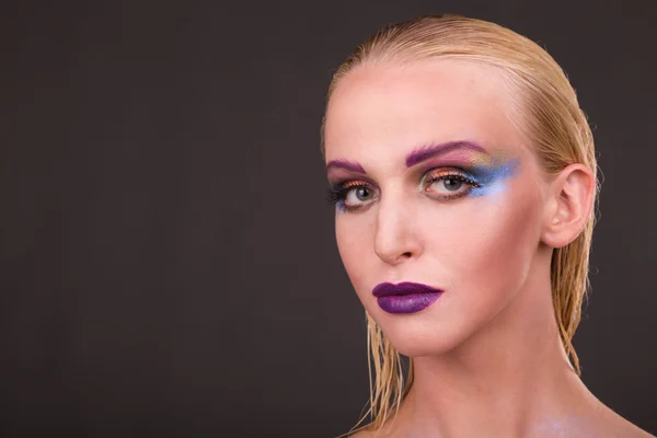 Schönes Modell mit Kunst-Make-up auf dunklem Hintergrund — Stockfoto