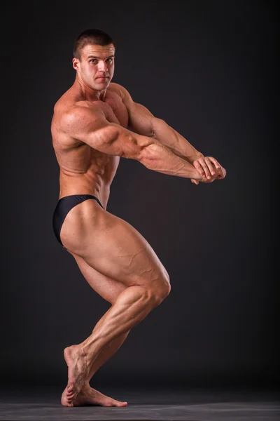 Professional bodybuilder shows his body on a dark background — Stock Photo, Image