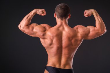 Profesyonel vücut geliştirmeci bedeni koyu arka plan üzerinde gösterir.