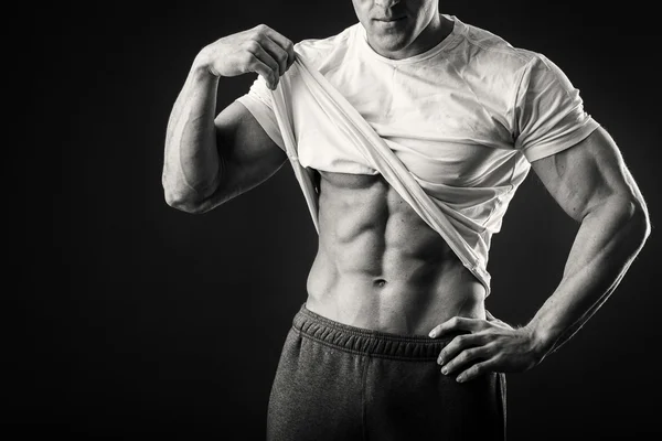 Muscular man in a sports jacket on a dark background — Stock Photo, Image