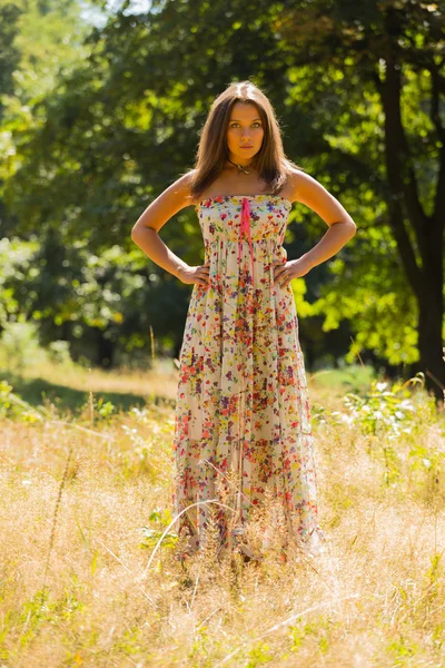 Young beautiful brunette in a dress middle of the park on a warm summer day — Stok fotoğraf