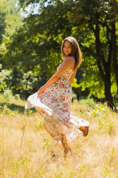 Young beautiful brunette in a dress middle of the park on a warm summer day — Zdjęcie stockowe