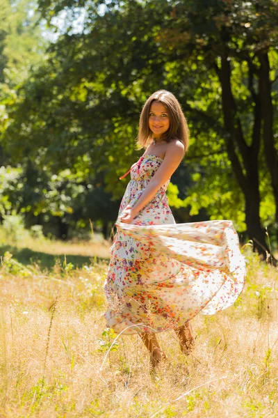 Young beautiful brunette in a dress middle of the park on a warm summer day — Stok fotoğraf