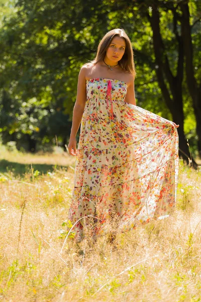 Young beautiful brunette in a dress middle of the park on a warm summer day — Stok fotoğraf