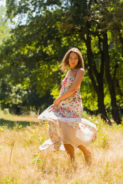 Young beautiful brunette in a dress middle of the park on a warm summer day — Stok fotoğraf