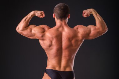 Profesyonel vücut geliştirmeci bedeni koyu arka plan üzerinde gösterir.