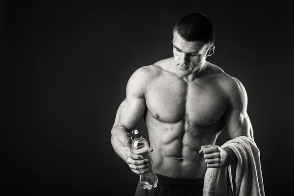 Muskularny mężczyzna na ciemnym tle wody pitnej po treningu — Zdjęcie stockowe