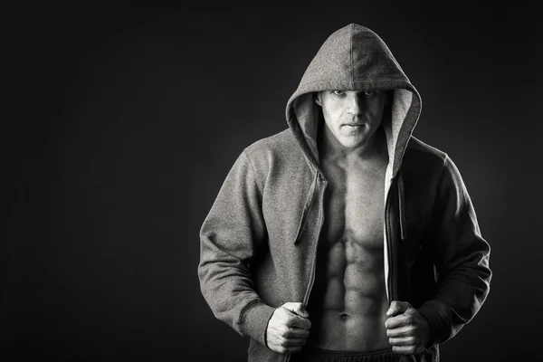 Homem muscular em uma jaqueta de esportes em um fundo escuro — Fotografia de Stock