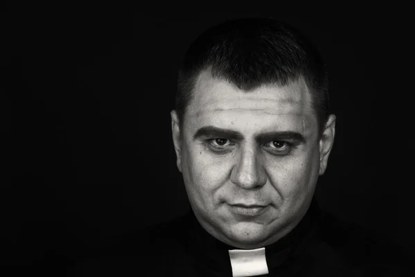 Un acteur de scène professionnel déguisé en prêtre sur fond sombre — Photo
