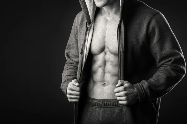 Homem muscular em uma jaqueta de esportes em um fundo escuro — Fotografia de Stock