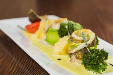 Beyaz bir tabakta sebze ile lezzetli kızarmış balık pişmiş