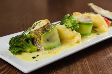 Beyaz bir tabakta sebze ile lezzetli kızarmış balık pişmiş