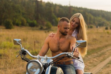 Kaslı adam bir motosiklet orta alan yolun üzerinde güzel bir kadınla