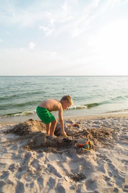 Sahilde kumda oynayan genç bir çocuk