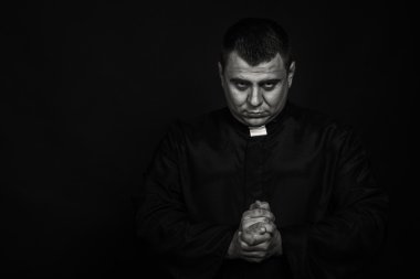 Karanlık bir arka plan karşı bir rahip kılığında bir profesyonel tiyatro oyuncusu