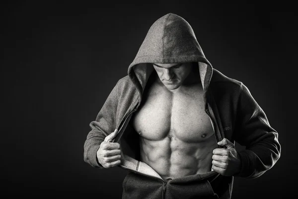 Homem muscular em uma jaqueta de esportes em um fundo escuro — Fotografia de Stock