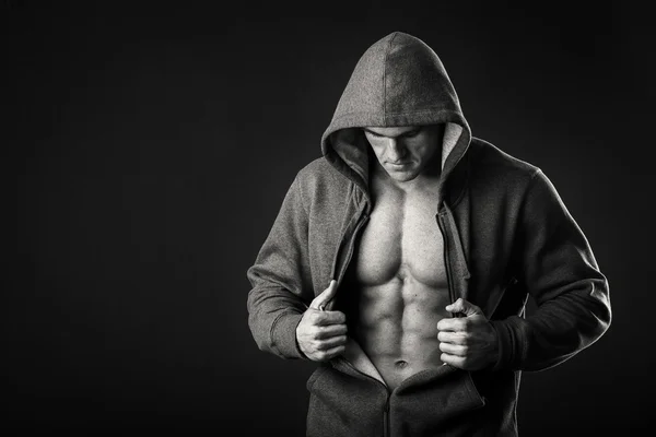 Мускулистый человек в спортивной куртке на темном фоне — стоковое фото