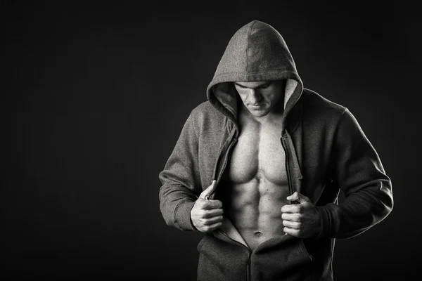 Homem muscular em uma jaqueta de esportes em um fundo escuro — Fotografia de Stock