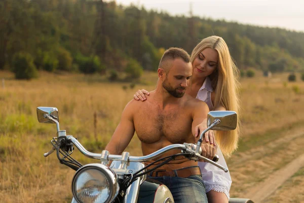 Kaslı adam bir motosiklet orta alan yolun üzerinde güzel bir kadınla