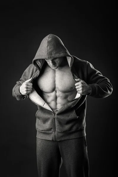 Homem muscular em uma jaqueta de esportes em um fundo escuro — Fotografia de Stock