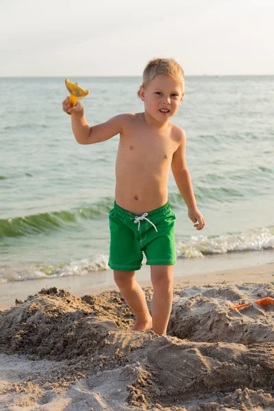 Sahilde kumda oynayan genç bir çocuk