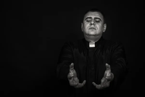 Un actor teatral profesional disfrazado de sacerdote sobre un fondo oscuro — Foto de Stock