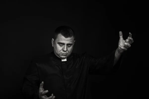 A professional stage actor in the guise of a priest against a dark background — Stock Photo, Image