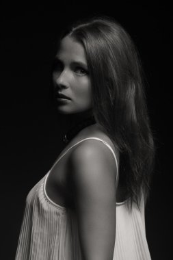 Karanlık bir arka plan üzerinde beyaz elbiseli güzel esmer