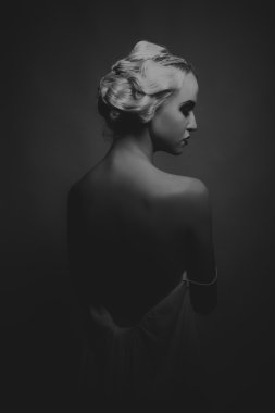 Karanlık bir arka plan üzerinde vintage elbiseli güzel sarışın