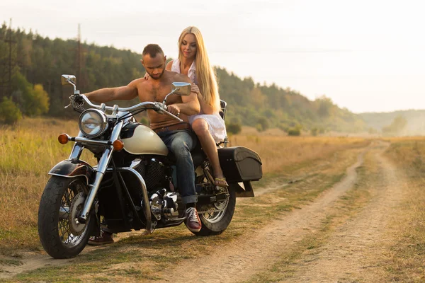 Kaslı adam bir motosiklet orta alan yolun üzerinde güzel bir kadınla