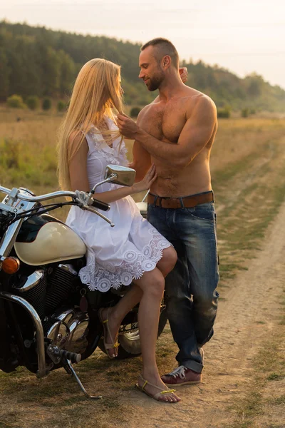 Kaslı adam bir motosiklet orta alan yolun üzerinde güzel bir kadınla