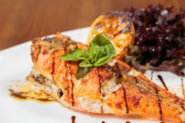 Beyaz bir tabakta sebze ile lezzetli kızarmış balık pişmiş