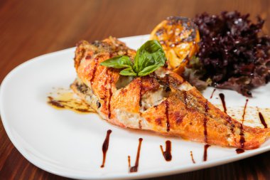 Beyaz bir tabakta sebze ile lezzetli kızarmış balık pişmiş