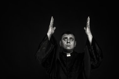 Karanlık bir arka plan karşı bir rahip kılığında bir profesyonel tiyatro oyuncusu