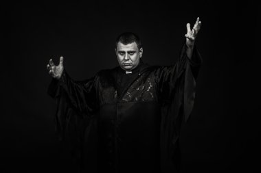 Karanlık bir arka plan karşı bir rahip kılığında bir profesyonel tiyatro oyuncusu