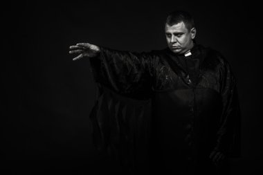 Karanlık bir arka plan karşı bir rahip kılığında bir profesyonel tiyatro oyuncusu