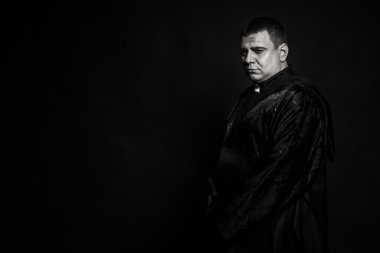 Karanlık bir arka plan karşı bir rahip kılığında bir profesyonel tiyatro oyuncusu