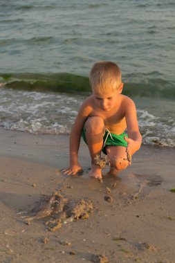 Sahilde kumda oynayan genç bir çocuk