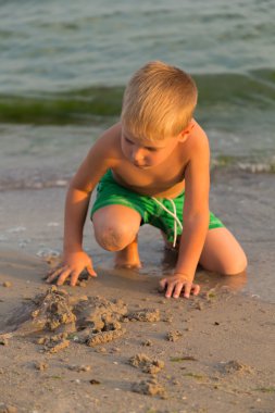 Sahilde kumda oynayan genç bir çocuk