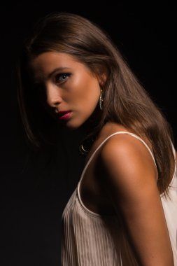 Karanlık bir arka plan üzerinde beyaz elbiseli güzel esmer