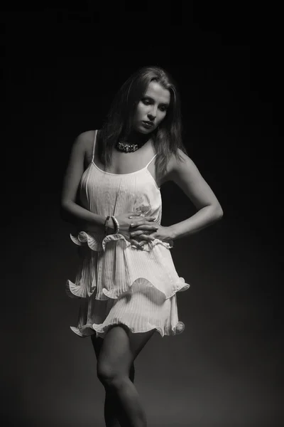 Beautiful brunette in a white dress on a dark background — Stock Photo, Image