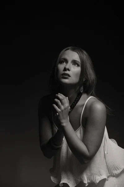 Beautiful brunette in a white dress on a dark background